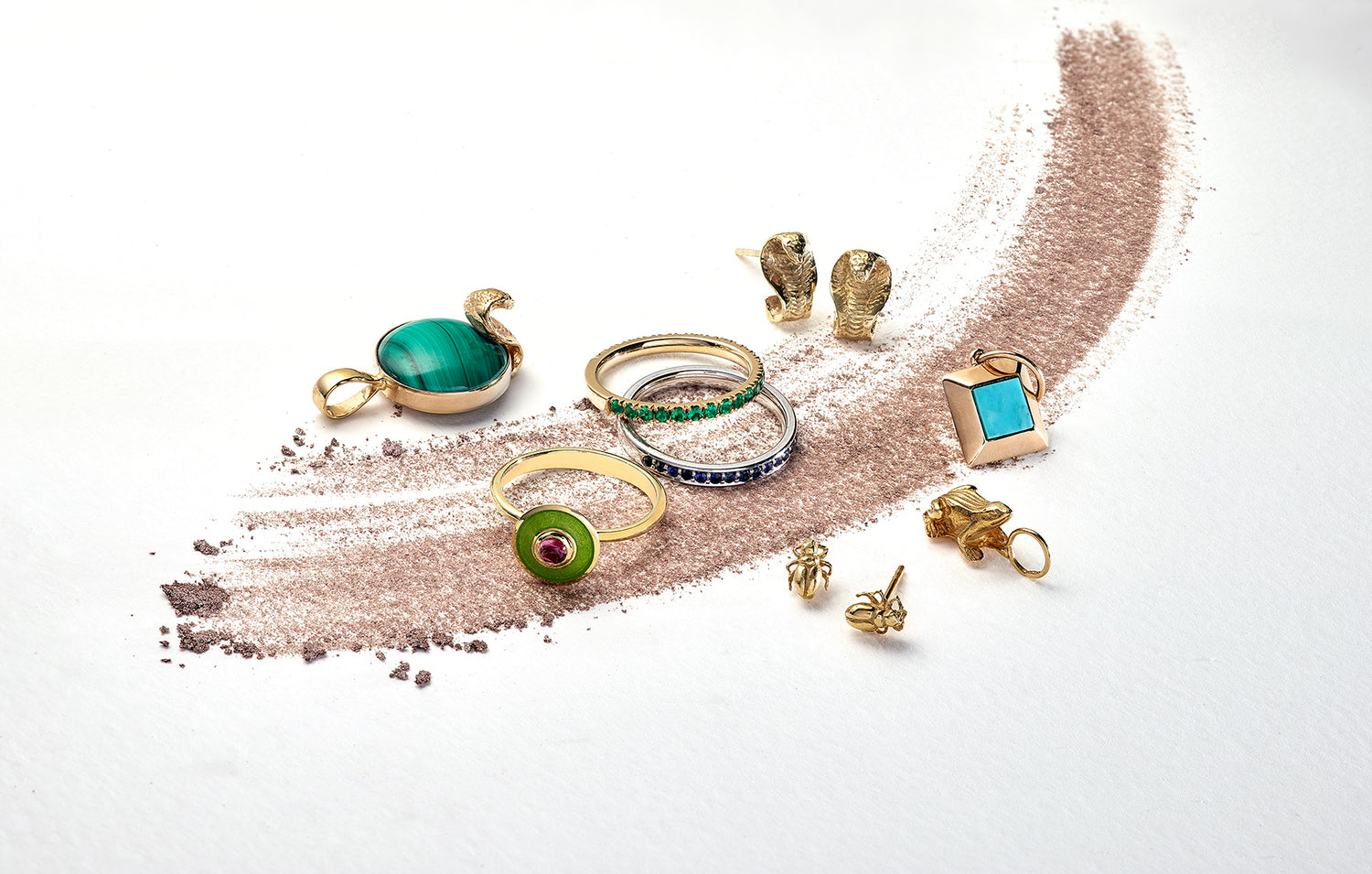 Jewellery design London, a collection of the Egyptian jewellery, frog for fertility, scarabs for rebirth, cobras for protection, and a turquoise pendant which is the outline of a Egyptian Pyramid.  Two eternity bands in Emeralds and Sapphire and one ity bity aurora vitreous enamel and pink tourmaline ring. 