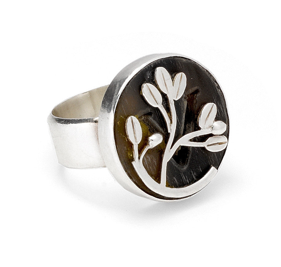 A silver round ring with horn carved with a V and silver olive branch laid over the horn