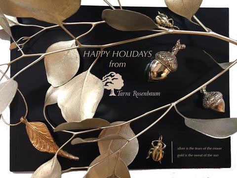 black and gold happy holiday announcement with gold charms of scarabs and acorns